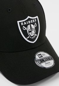 Melnā beisbola cepure ar izšūtu balto Raiders logotipu priekšpusē. Regulējama siksna. Izgatavota no teksturēta auduma.