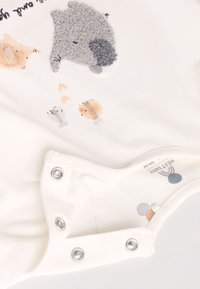 Body blanco para bebé con ilustraciones de animales en textura suave en colores gris, beige y tonos pastel claros. Cierres de broche en la parte inferior.