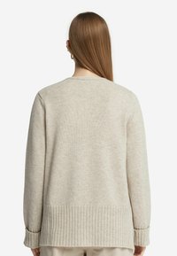 Beige stickad tröja med ribbad nederkant och mudd, med rund halsringning och avslappnad passform, visad från baksidan.