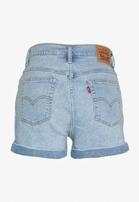 Pantalones cortos de mezclilla de color azul claro con dobladillos enrollados, que presentan dos bolsillos traseros y una etiqueta de marca de cuero marrón en la cinturilla.