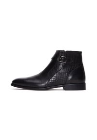 Botín de cuero negro con correa de hebilla lateral y panel texturizado, tacón bajo, punta lisa y estilo de deslizamiento.