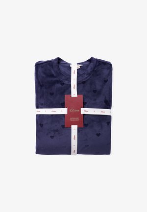 Haut en tissu doux bleu marine avec de petits motifs en forme de cœur, plié soigneusement et maintenu avec un ruban blanc arborant une étiquette de marque indiquant la taille petite.