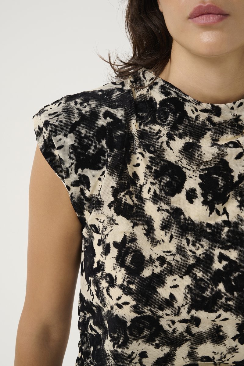 Ärmelloses Top in Schwarz mit cremefarbenem Muster, aus weichem Material und mit lockerer Passform. Es hat einen runden Halsausschnitt und leicht geraffte Schultern.