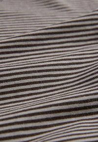 Gros plan d’un tissu froissé avec des rayures horizontales marron foncé et beige créant un motif texturé.
