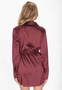 Rochie din satin burgundy, cu guler, mâneci lungi și talie elastică. Prezintă o textură netedă și manșete de tip cămașă.