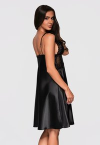 Vestito da notte in satin nero con dettagli in pizzo, spalline sottili regolabili e gonna a strati. Texture liscia e silhouette classica.