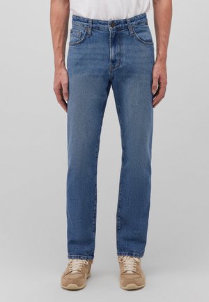 Light blue denim jeans with a straight cut, featuring five pockets, a zipper fly, and a subtle faded texture. Worn with beige sneakers.
