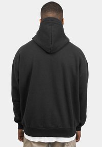 Sort hættetrøje med en afslappet pasform, ribbede manchetter og kant. Stoffet ser blødt og let tekstureret ud.