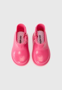 Pink rubber shoes with a glossy finish, rounded toe, and ankle height. Features a zipper on the side and a patterned insole.