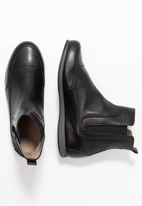 Černé kožené kotníkové boty s hladkým povrchem, elastickými bočními panely, zaoblenou špičkou a plochou gumovou podrážkou.