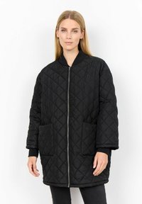 Svart quiltad jacka med ståkrage, frontdragkedja och fickor med lappar. Har diamantmönster och textilstruktur. Långa ärmar.
