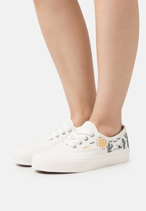 Hvide lavtsiddende vævede sneakers med snørebånd og broderede kaktus- og solmotiver, båret på bare ben.
