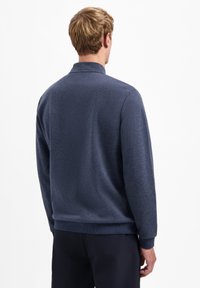 Marineblauwe pullover met een gestructureerde afwerking, geribde manchetten en een hoge kraag. Heeft een relaxte pasvorm en een schoon ontwerp.