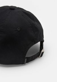 Fekete pamut sapka ívelt csúccsal, állítható pánttal a hátulján, és egy kis márkacímkével az oldalán. Simma textúra, minta nélkül.