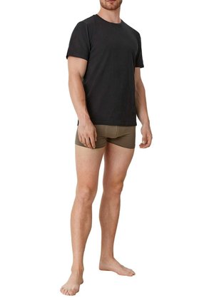 Schwarzes T-Shirt mit kurzen Ärmeln, runder Ausschnitt, kombiniert mit olivgrünen Boxershorts, getragen von einer männlichen Figur mit baren Füßen, die aufrecht steht.