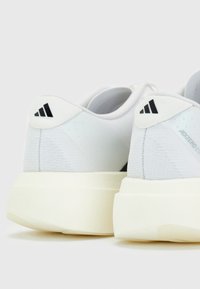 Paire de chaussures de course blanches Adidas Adizero vues de dos, avec un logo Adidas noir sur le talon et des semelles épaisses blanc cassé.
