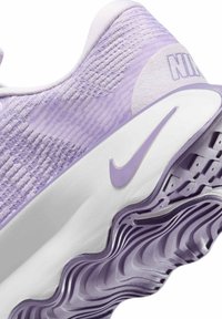 Baskets Nike lilas clair avec une tige en mesh texturé, une semelle intermédiaire blanche et une semelle extérieure ondulée violette avec des rainures pour l'adhérence.