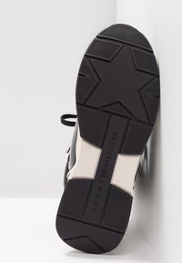 Czarnobiała podeszwa trampka z wzorem gwiazdy, teksturowana guma, wyraźna nazwa marki "TOMMY HILFIGER" oraz oznaczenie rozmiaru "37".