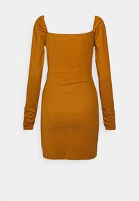 Vestido ajustado de mangas longas em amarelo mostarda, feito de um tecido suave e texturizado. Apresenta um decote quadrado e detalhes franzidos nos ombros.