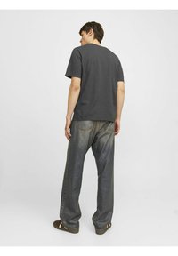 Dunkelgraues T-Shirt mit kurzen �Ärmeln, kombiniert mit locker sitzenden blauen Jeans aus Denim, die ein gerades Bein-Design und minimale Nähte aufweisen.