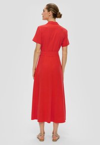 Rotes Midi-Kleid mit kurzen Ärmeln, tailliertem Bund und einem schwingenden Rock. Glatte Textur, schlichtes Design und dezente Kragenakzente.