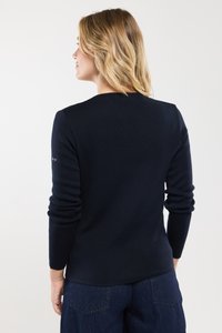 Granatowy sweter z prążkowanej dzianiny, o okrągłym dekolcie, długich rękawach i subtelnym detalu z logo na lewym rękawie. Miękka tekstura, dopasowany krój.