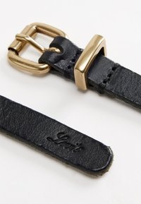 Μαύρη δερμάτινη ζώνη με χρυσή μεταλλική αγκράφα. Έχει λεία υφή και λογότυπο με ανάγλυφη σφραγίδα. Η αγκράφα είναι ορθογώνια με κλείσιμο πινέζας.