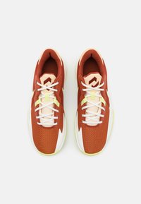 Czerwone buty sportowe z teksturowanej tkaniny, białymi sznurówkami, żółtymi akcentami i wyraźną białą podeszwą. Posiadają charakterystyczny geometryczny wzór na górnej części.