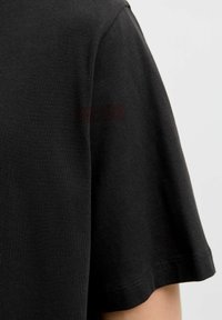 Sort kortærmet T-shirt lavet af blødt stof med en rund halsudskæring og syet kant. Teksturen er glat og ensartet.
