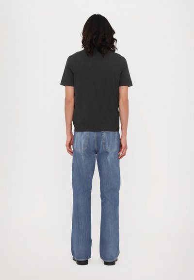 Tmavošedé tričko s krátkym rukávom spárované so svetlomodrými rozšírenými džínsami. Tkanina vyzerá mäkko; džínsy majú zadné vrecká a ležérne šitie.