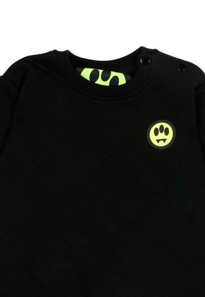 Zwarte sweatshirt met ronde halslijn, twee zwarte knopen op de schouder, en een neongeel vampier-potenafdruklogo op de borst.