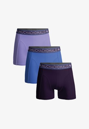 Tre paia di boxer da uomo in lavanda, blu e viola scuro. Ognuno presenta un morbido elastico con motivo "MUCHACHO". Texture del tessuto liscia.