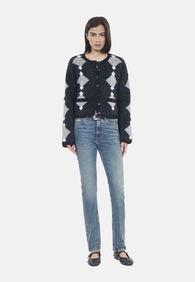 Cardigan a maglia a righe nere e grigie con scollatura rotonda e bottoni, abbinato a jeans a gamba dritta azzurri chiari e scarpe basse nere.
