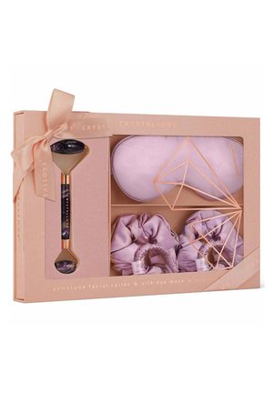 Gemstone facial roller with a purple stone and gold accents, paired with a silk eye mask and two lavender silk scrunchies, packaged in a pastel box.