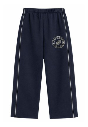 Pantalones azul marino de pierna ancha con cintura elástica, franjas laterales blancas y logo circular con hoja y texto "Sweet Pants Since 1982" en el muslo izquierdo.