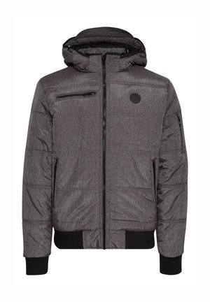 Giacca puffer grigia trapuntata con cappuccio, dotata di tasche frontali con zip, polsini a coste e un logo circolare sul petto. Texture liscia.