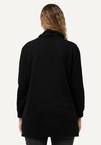 Sudadera negra de manga larga con un cuello drapeado y un corte relajado. Tejido suave y liso con una parte trasera ligeramente más larga y puños acanalados.