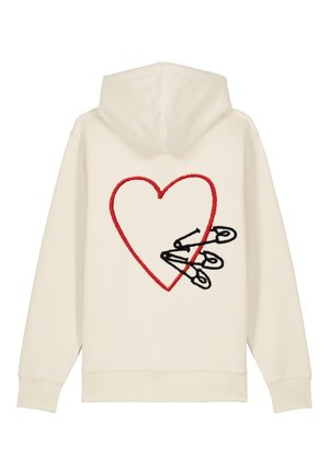Sweat à capuche crème avec un grand cœur rouge brodé et des épingles de sécurité noires croisées au dos. Texture douce, design décontracté.