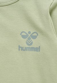 Jasnozielona bawełniana koszulka z grafiką niebieskiego pszczoły oraz napisem "hummel" poniżej. Gładka faktura z okrągłym dekoltem.