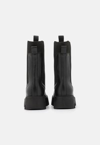 Black ankle boots featuring a combination of leather and knit material, with a chunky sole and pull-tabs at the back for easy wear.