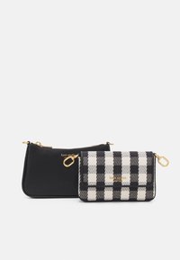 Portefeuille en tissu à carreaux noir et blanc avec une tirette dorée et un logo, associé à une pochette noire unie avec un anneau d'attache doré.