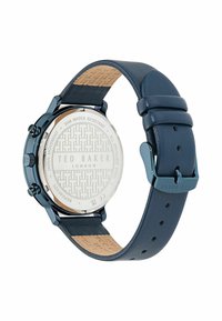 Reloj redondo de acero inoxidable azul con correa de cuero oscura. Presenta una parte posterior en plata texturizada con el logo y la indicación de resistencia al agua.