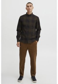 Long-sleeve black and brown checkered shirt with a button-down collar, paired with brown corduroy pants and black sneakers.