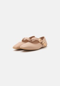 Bailarinas beige con punta afilada, suela plana y un acento decorativo de hebilla dorada con una correa ajustable sobre el pie.