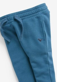 Blaue Baumwoll-Sweatpants mit einem elastischen Bund und Kordelzug, versehen mit einem kleinen gestickten Dinosaurier-Logo am linken Oberschenkel.