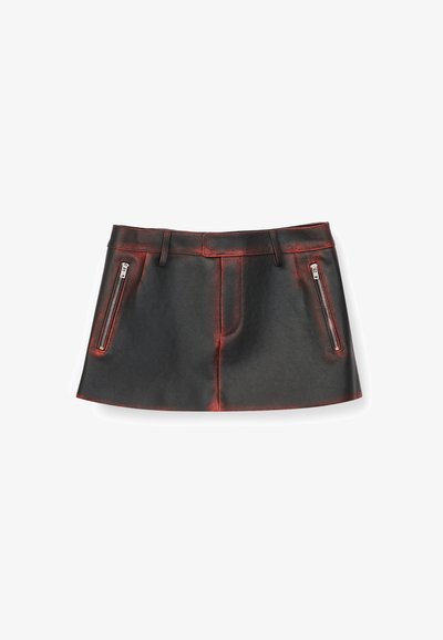 Minigonna in similpelle nera con due tasche verticali con cerniera e passanti per cintura, con sottili dettagli rossi lungo le cuciture.
