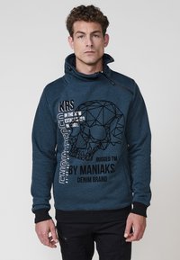 Sudadera azul marino con un patrón texturizado, que presenta un gráfico de calavera geométrica y texto en blanco. Cuello ajustable y puños negros.