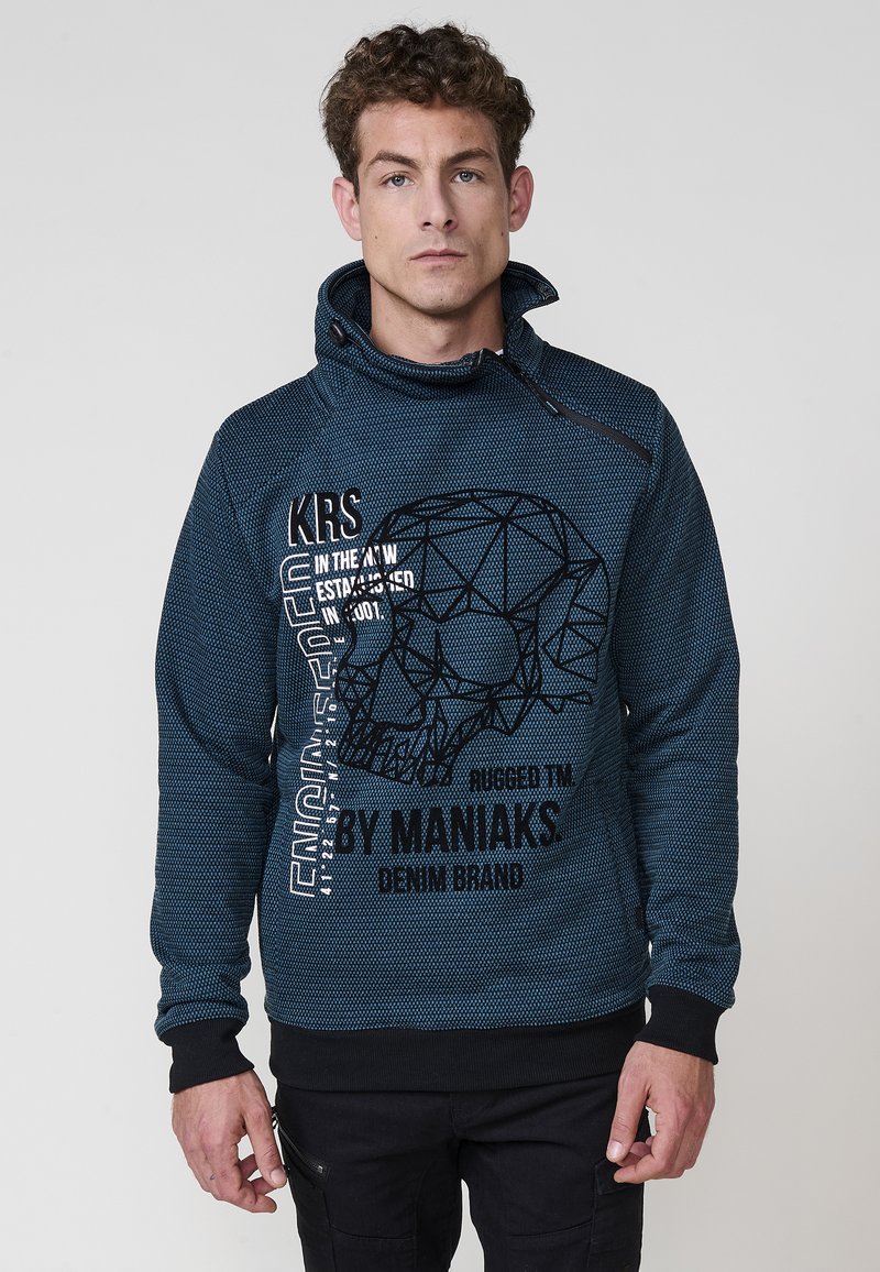 Sudadera azul marino con un patrón texturizado, que presenta un gráfico de calavera geométrica y texto en blanco. Cuello ajustable y puños negros.