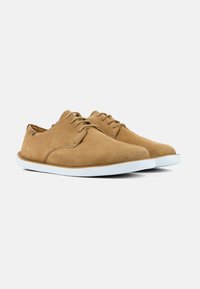 Scarpe in suede marrone con una texture liscia, dotate di suola in gomma bianca e un design tradizionale con lacci. Nessun motivo o accento visibile.