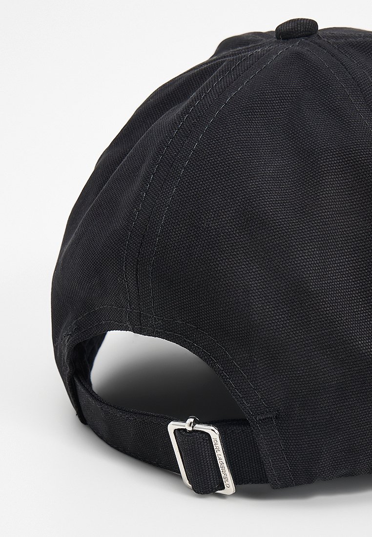 Casquette noire en tissu texturé avec un visière incurvée, sangle ajustable à l'arrière avec une boucle en métal argenté et un détail de marque.